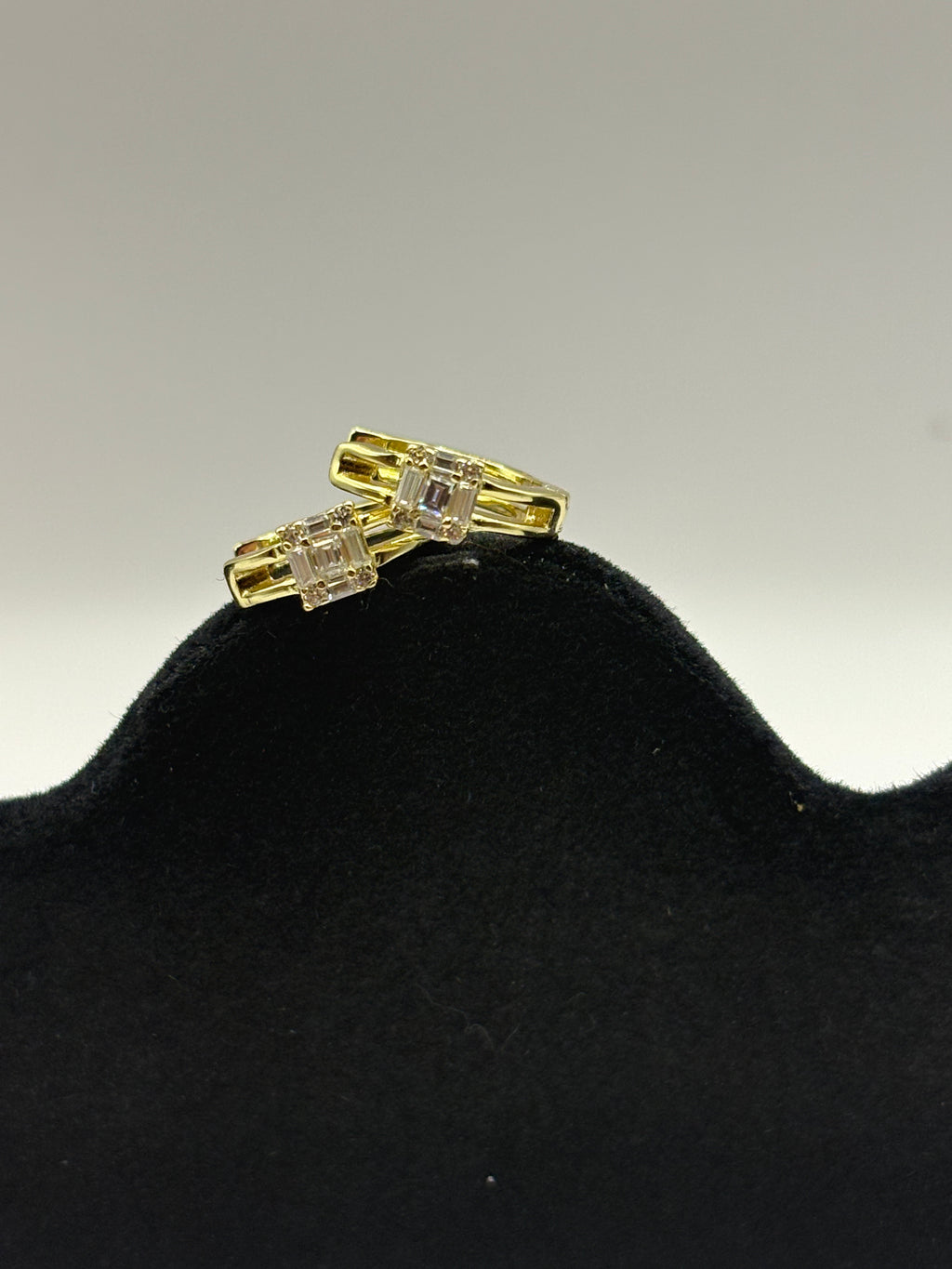 Huggie hoop earrings feature a distinctive open split-shank band and a geometric moissanite cluster design