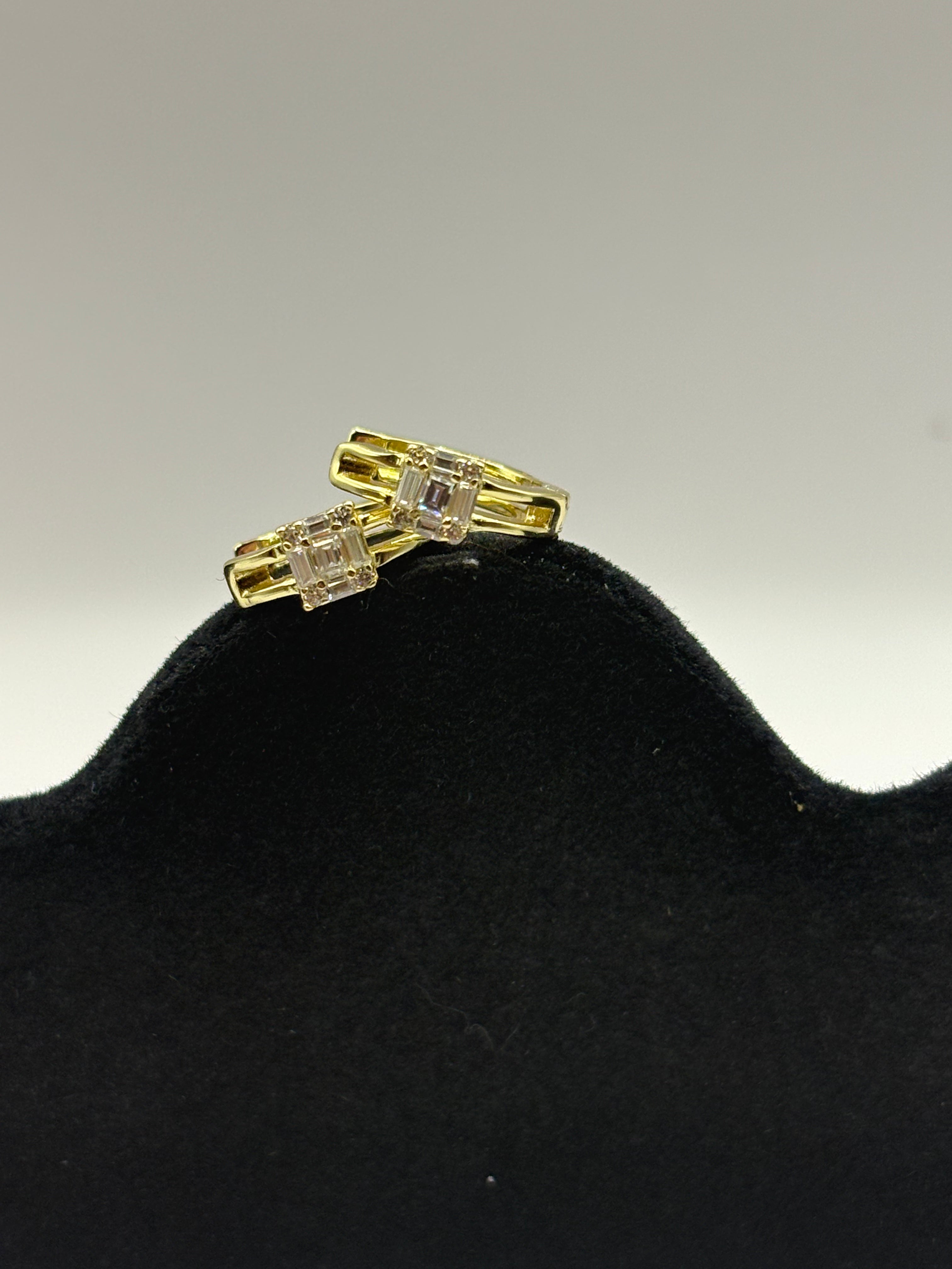 Huggie hoop earrings feature a distinctive open split-shank band and a geometric moissanite cluster design