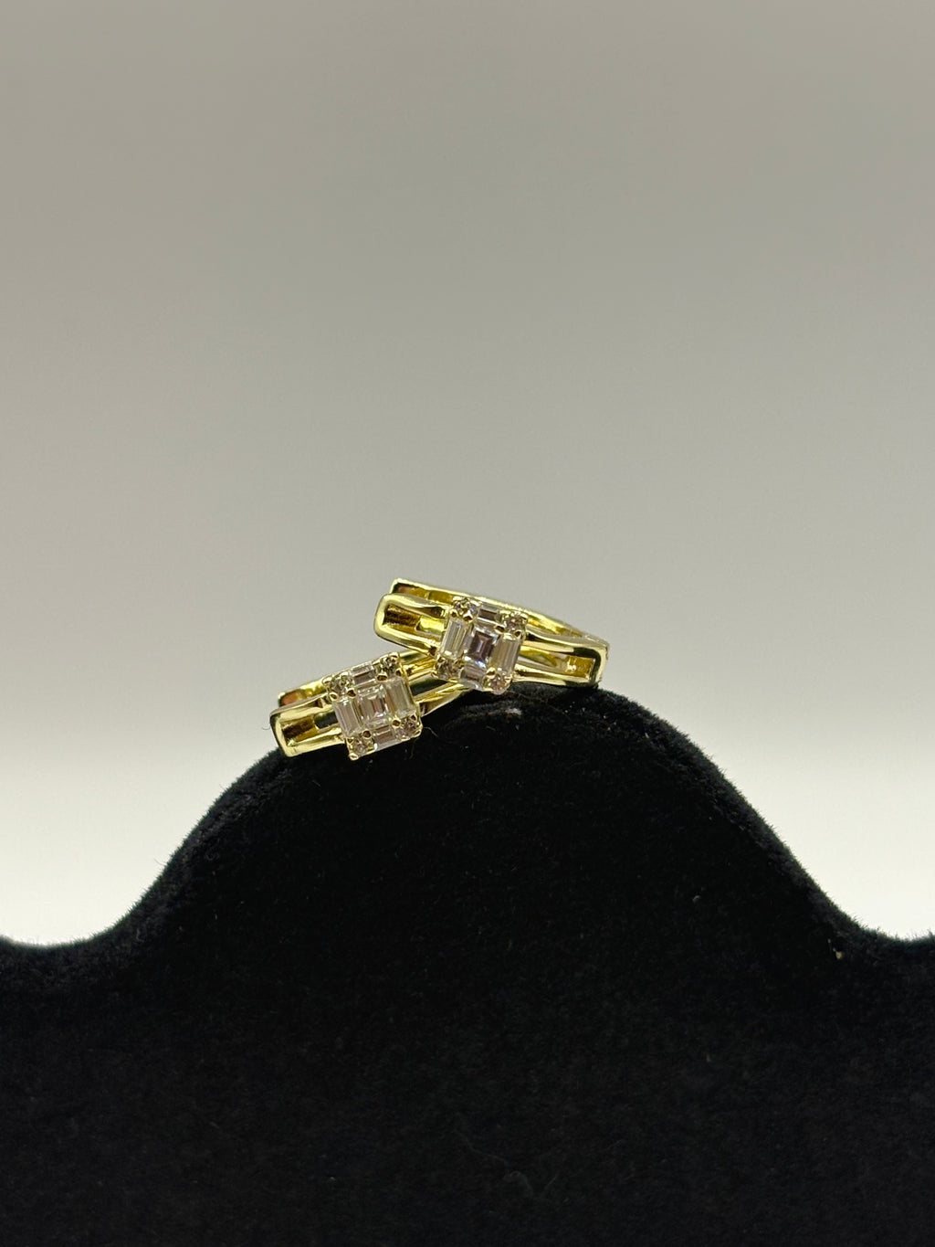 Huggie hoop earrings feature a distinctive open split-shank band and a geometric moissanite cluster design