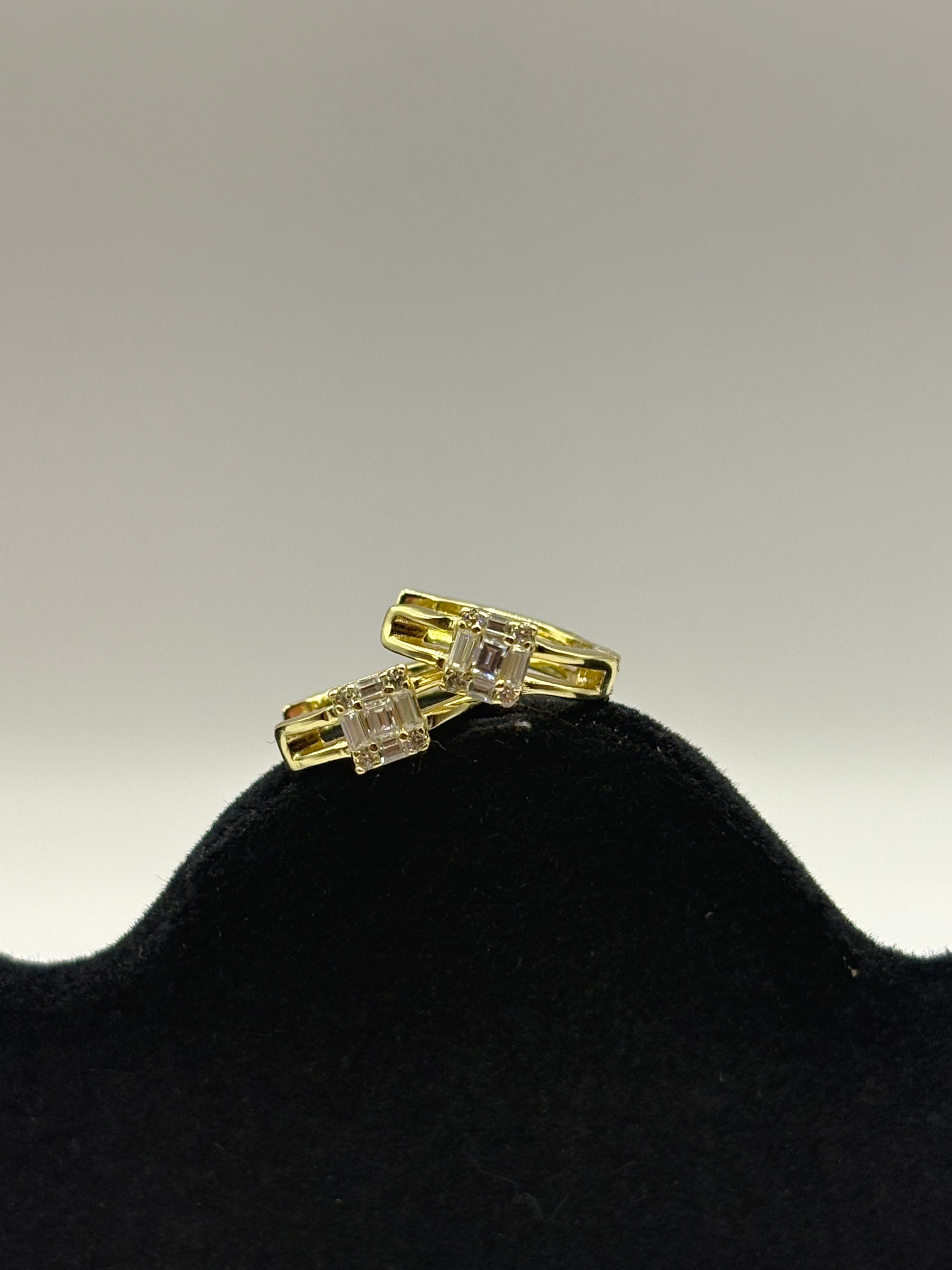 Huggie hoop earrings feature a distinctive open split-shank band and a geometric moissanite cluster design