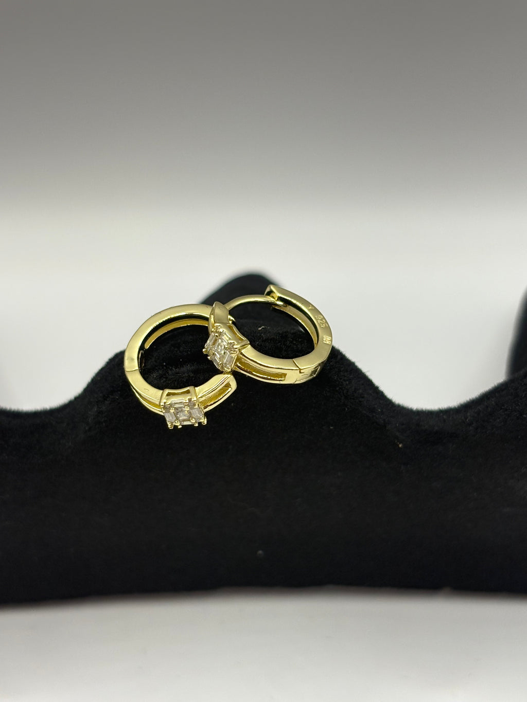 Huggie hoop earrings feature a distinctive open split-shank band and a geometric moissanite cluster design